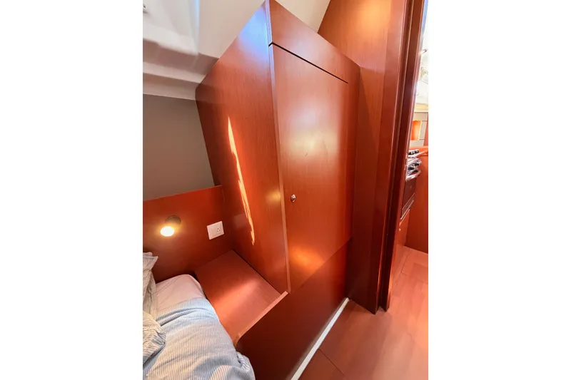 Slide: The Image of Interior of 2018 Beneteau Oceanis 35.1 yacht, featuring wooden cabinetry and cozy sleeping area. - 47
