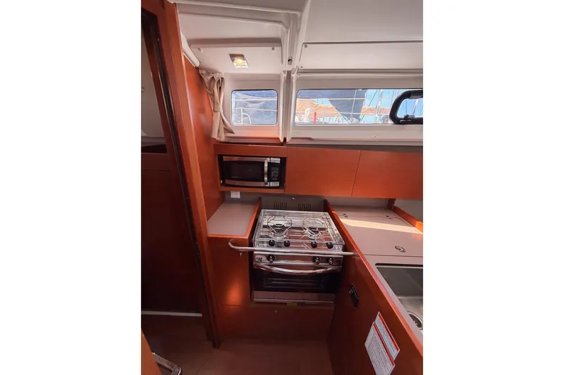 Slide: The Image of 2018 Beneteau Oceanis 35.1 yacht kitchen with stove, microwave, and window view. - 38