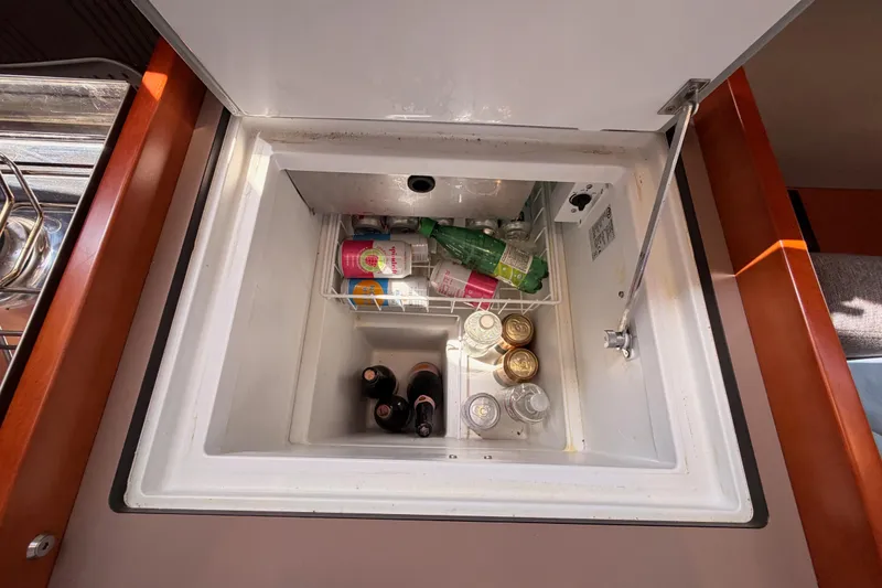 Slide: The Image of Refrigerator inside 2018 Beneteau Oceanis 35.1 yacht, stocked with beverages and bottles. - 41