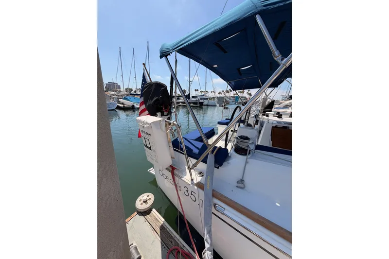 Slide: The Image of 2018 Beneteau Oceanis 35.1 sailboat docked in a marina, featuring a blue canopy. - 8