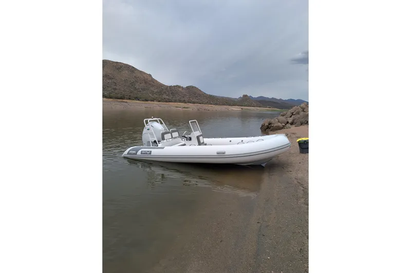 The Image of Tide Craft Kodiak 16 boat on a sandy shore, 2027 model, with scenic mountain backdrop. - 0
