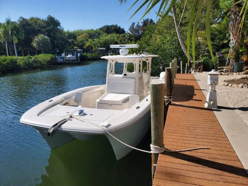 The Image of A white Calcutta 323 boat is docked at a wooden pier in a tranquil canal. - 0