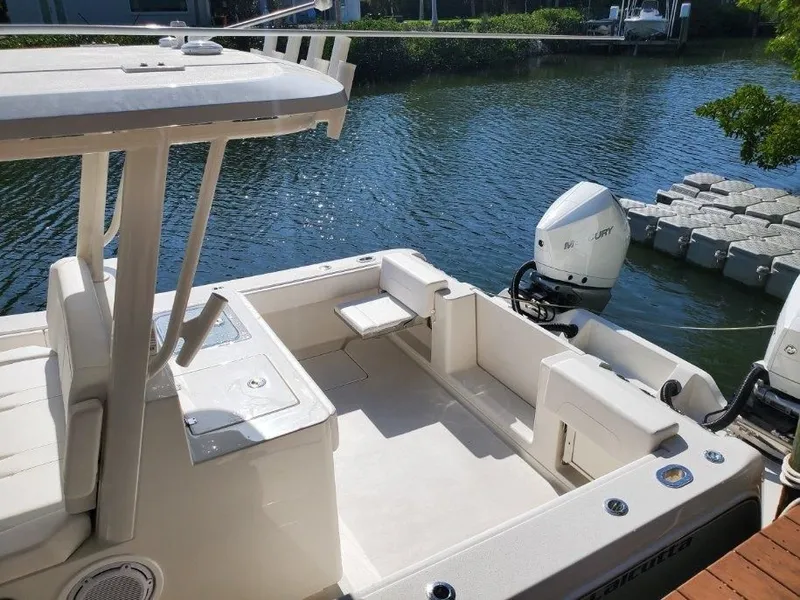 Slide: The Image of The image shows a modern boat with an open deck and twin outboard motors, docked by a calm waterway. - 4