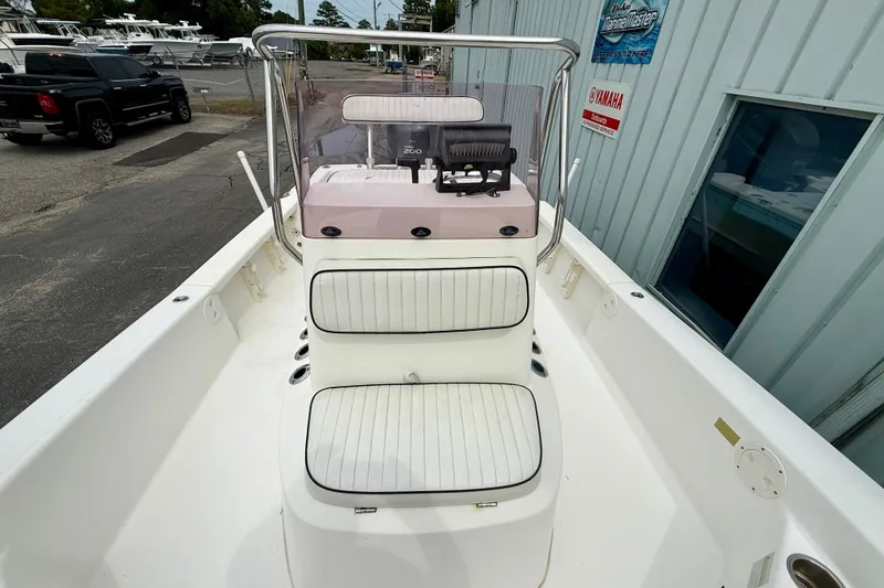 Slide: The Image of 2005 BlackJack 224 boat interior with white seating and console, docked near a building. - 7