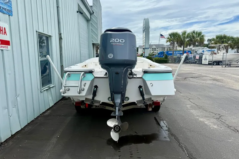 Slide: The Image of 2005 BlackJack 224 boat with Yamaha 200 engine, parked near a service building. - 3