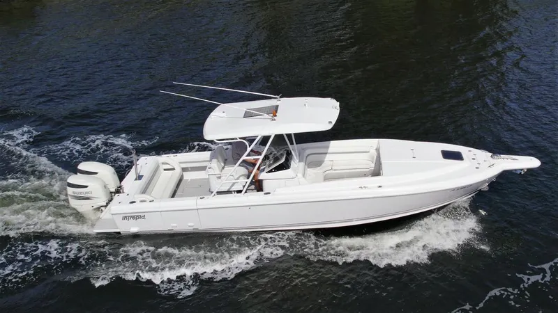 Slide: The Image of 2003 Intrepid 32 boat cruising on water, featuring sleek white design and dual outboard engines. - 0