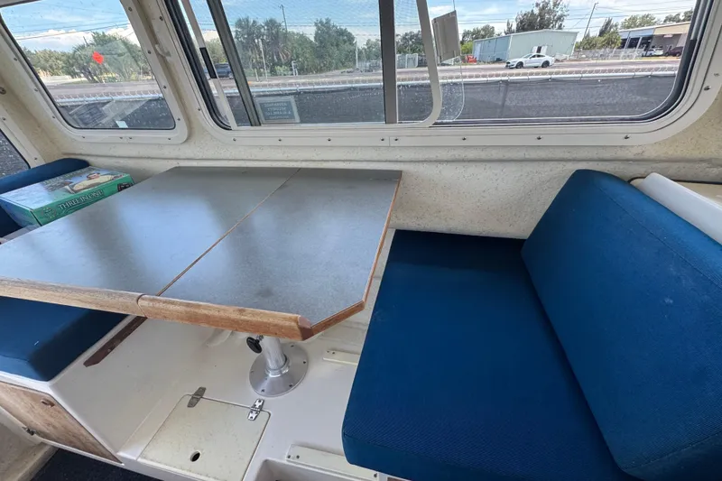 Slide: The Image of Interior of a 2013 C-Dory 22' Cruiser with blue seating and a foldable table. - 45