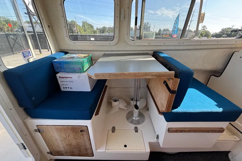 Slide: The Image of Interior of a 2013 C-Dory 22' Cruiser with blue seating and a compact table. - 12