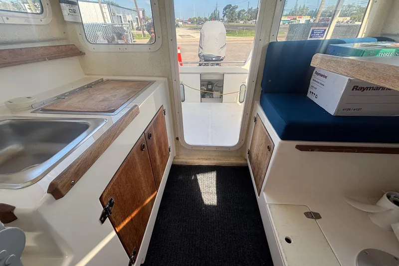 Slide: The Image of Interior of a 2013 C-Dory 22' Cruiser boat with kitchenette and seating area. - 24