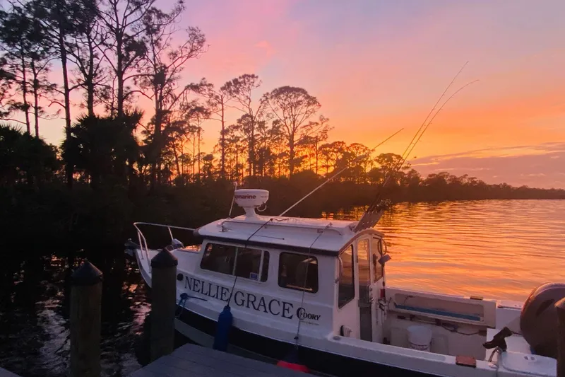 Slide: The Image of 2013 C-Dory 22' Cruiser docked at sunset with vibrant sky and trees. - 2