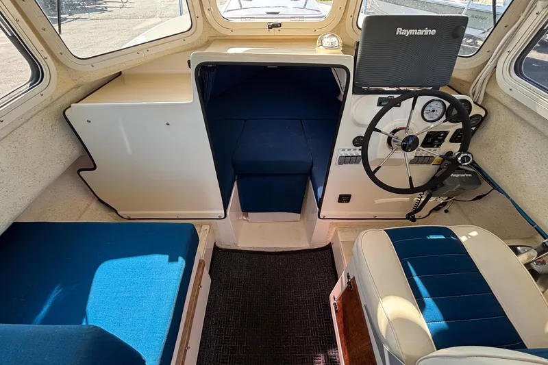 Slide: The Image of Interior of a 2013 C-Dory 22' Cruiser with blue upholstered seating and a helm station. - 13