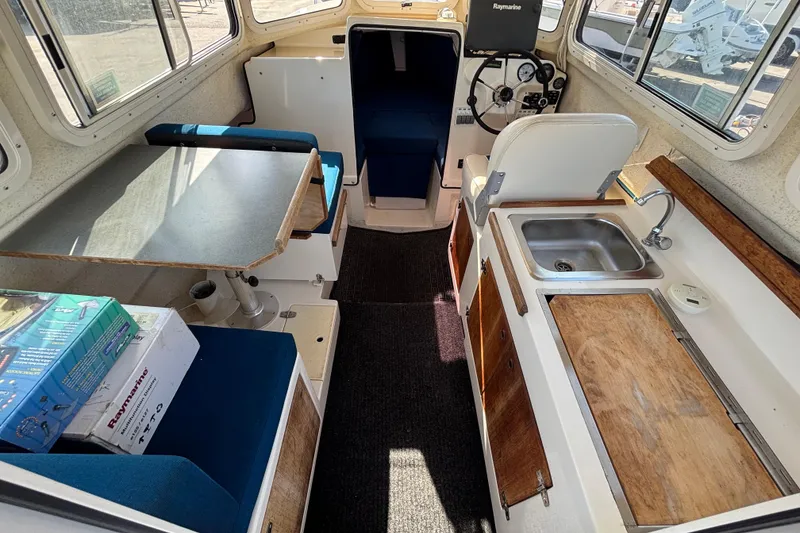 Slide: The Image of 2013 C-Dory 22' Cruiser interior with kitchenette, seating, and steering console. - 9