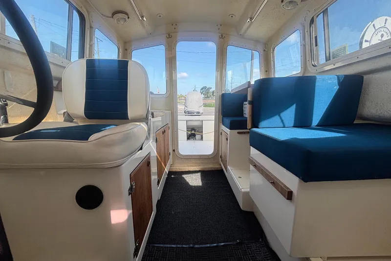 Slide: The Image of Interior of 2013 C-Dory 22' Cruiser with blue seating and wooden accents. - 22