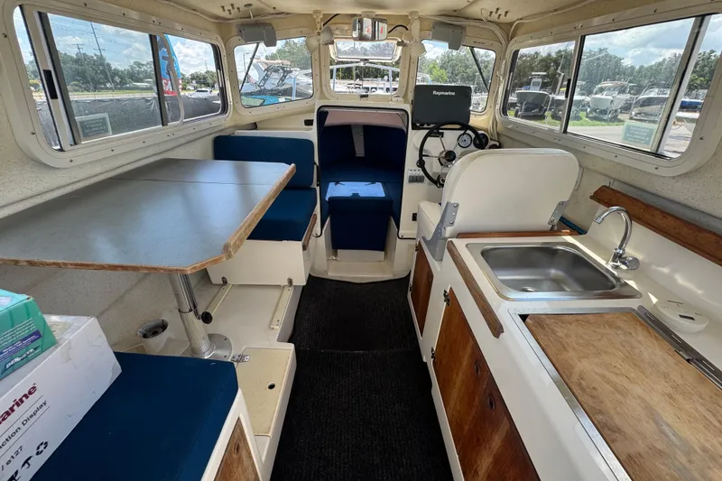 Slide: The Image of Interior of a 2013 C-Dory 22' Cruiser with seating, table, and kitchenette. - 25
