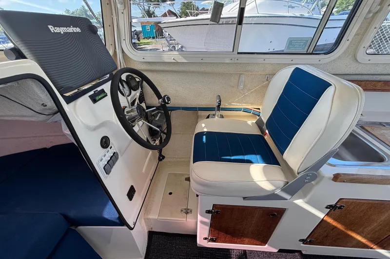 Slide: The Image of Interior of a 2013 C-Dory 22' Cruiser with steering wheel and blue seating. - 16