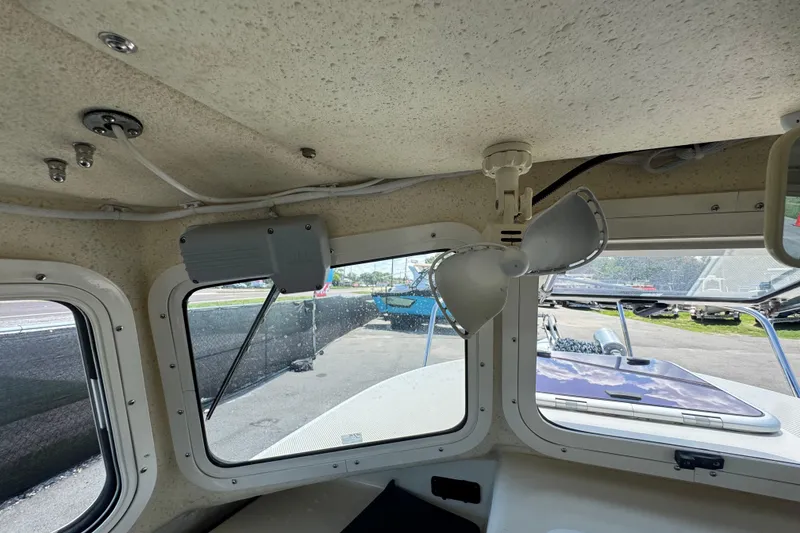 Slide: The Image of Interior view of a 2013 C-Dory 22' Cruiser boat, showcasing windows and a ceiling fan. - 30