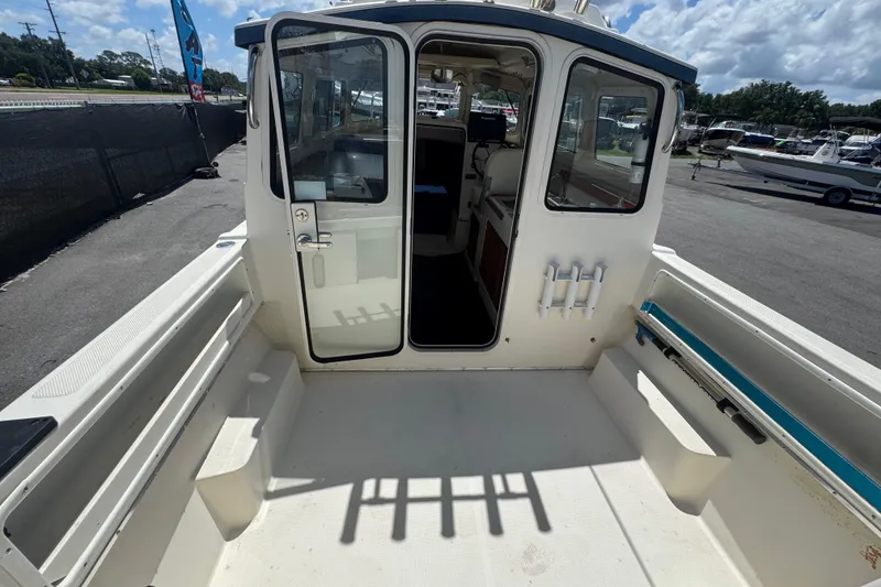 Slide: The Image of 2013 C-Dory 22' Cruiser boat with open cabin door, docked under a cloudy sky. - 22