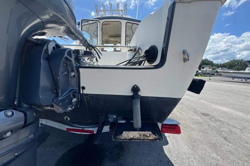 Slide: The Image of 2013 C-Dory 22' Cruiser boat stern view with outboard motor, parked on a sunny day. - 8