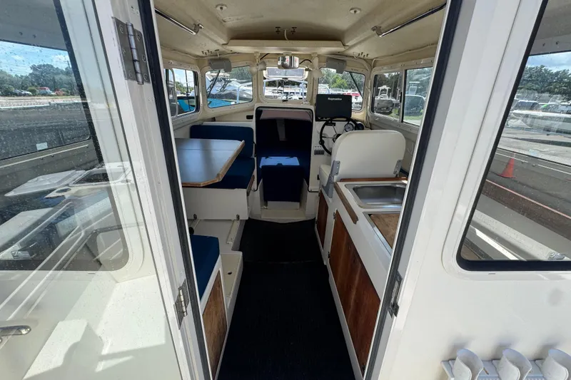 Slide: The Image of Interior view of a 2013 C-Dory 22' Cruiser, featuring seating and a compact kitchen area. - 24