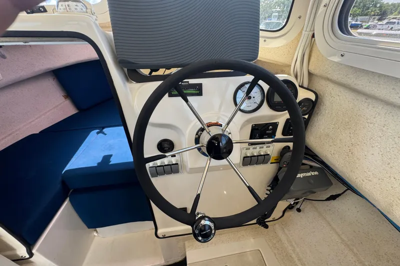 Slide: The Image of 2013 C-Dory 22' Cruiser helm with steering wheel, gauges, and blue seating. - 34