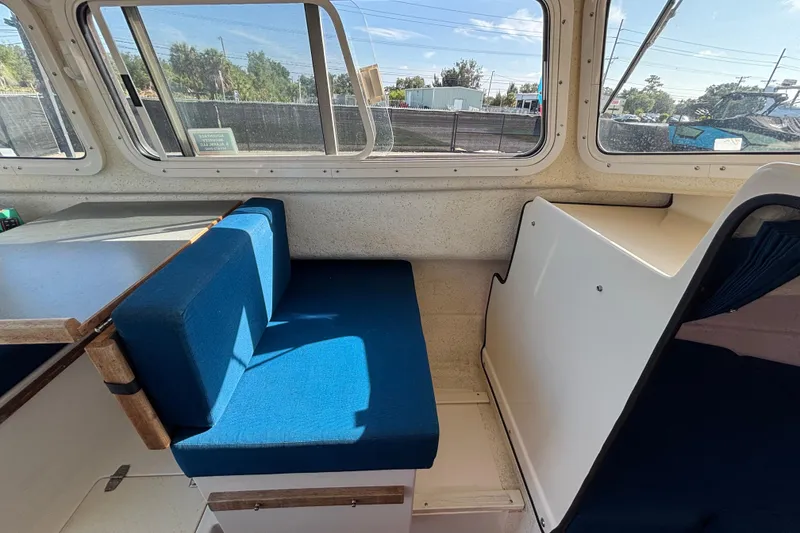 Slide: The Image of Interior of a 2013 C-Dory 22' Cruiser with blue seating and large windows. - 15