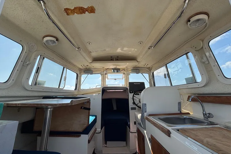 Slide: The Image of Interior of a 2013 C-Dory 22' Cruiser with seating area, helm, and small kitchenette. - 10