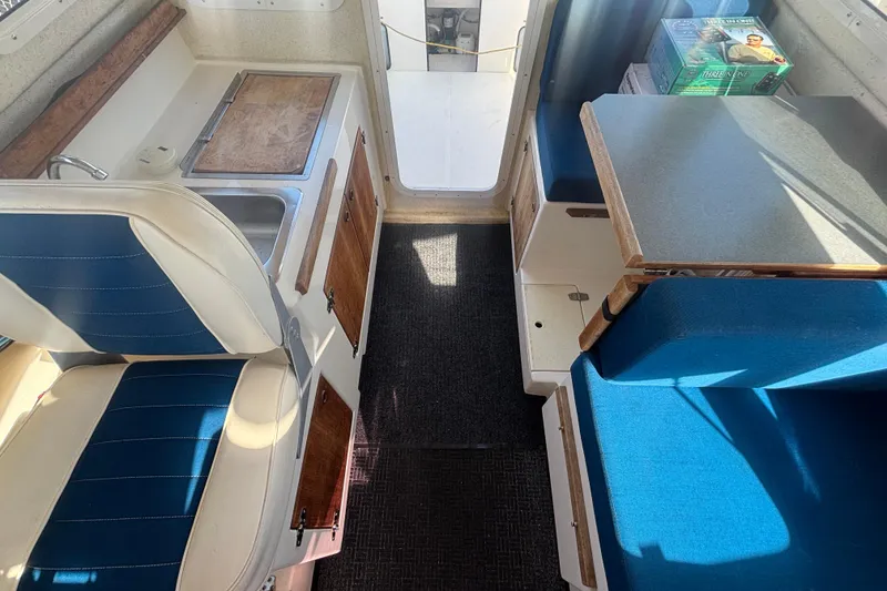 Slide: The Image of Interior of a 2013 C-Dory 22' Cruiser with seating, table, and kitchenette. - 23