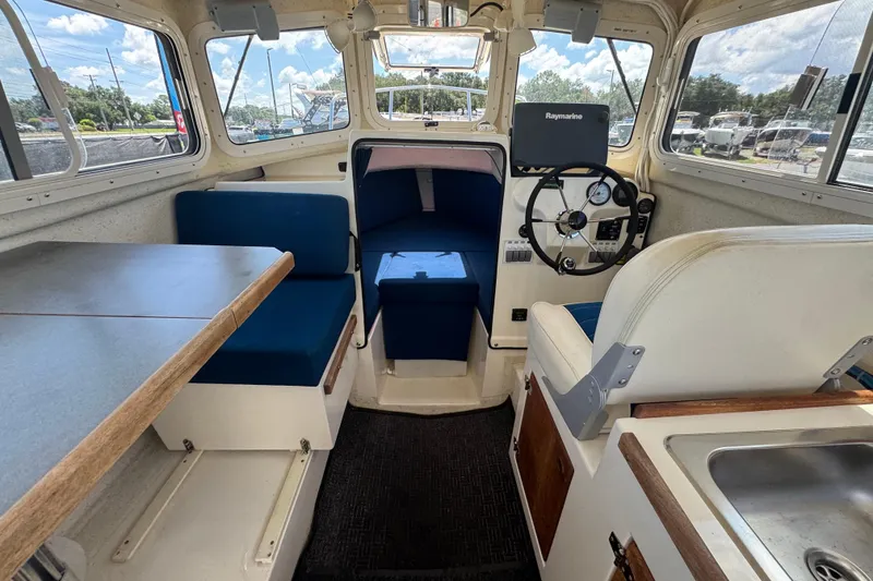 Slide: The Image of Interior of a 2013 C-Dory 22' Cruiser with seating, table, and steering wheel. - 28