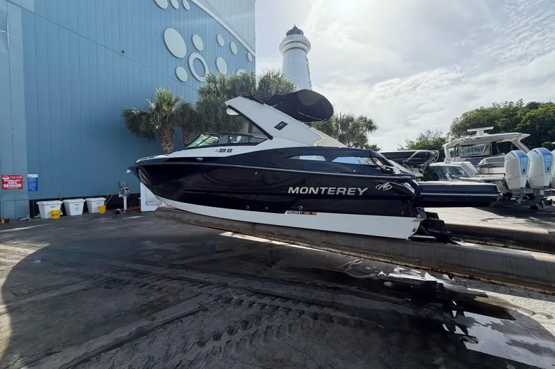 Slide: The Image of 2013 Monterey 328SS Super Sport boat on a dock, with a lighthouse and palm trees nearby. - 4