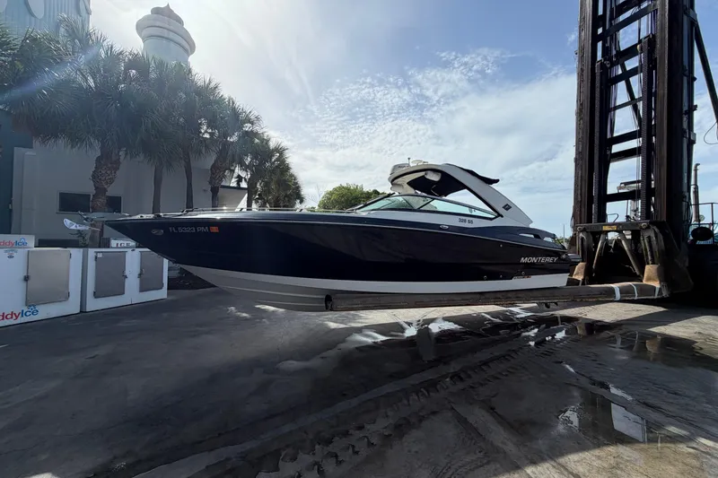 Slide: The Image of 2013 Monterey 328SS Super Sport boat lifted by forklift near palm trees. - 2