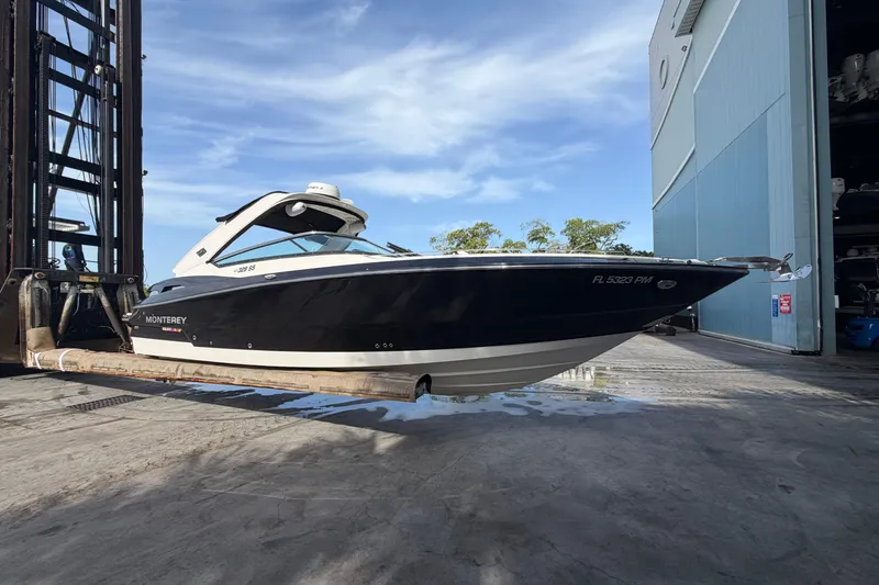 The Image of 2013 Monterey 328SS Super Sport boat lifted by forklift near storage facility. - 0