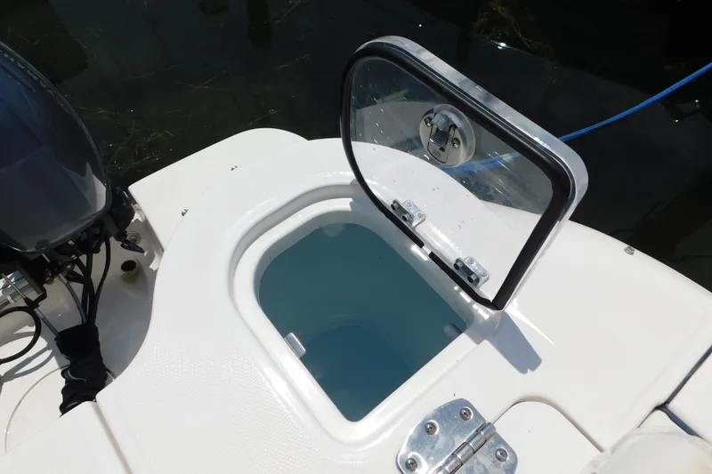 Slide: The Image of Open hatch on 2018 Robalo R247 Dual Console boat, revealing storage compartment. - 12