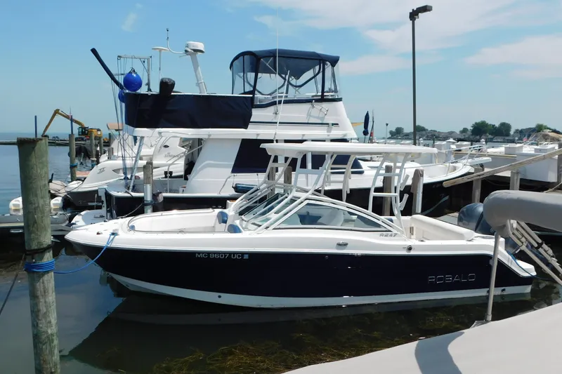 Slide: The Image of 2018 Robalo R247 Dual Console boat docked at a marina under a clear sky. - 1