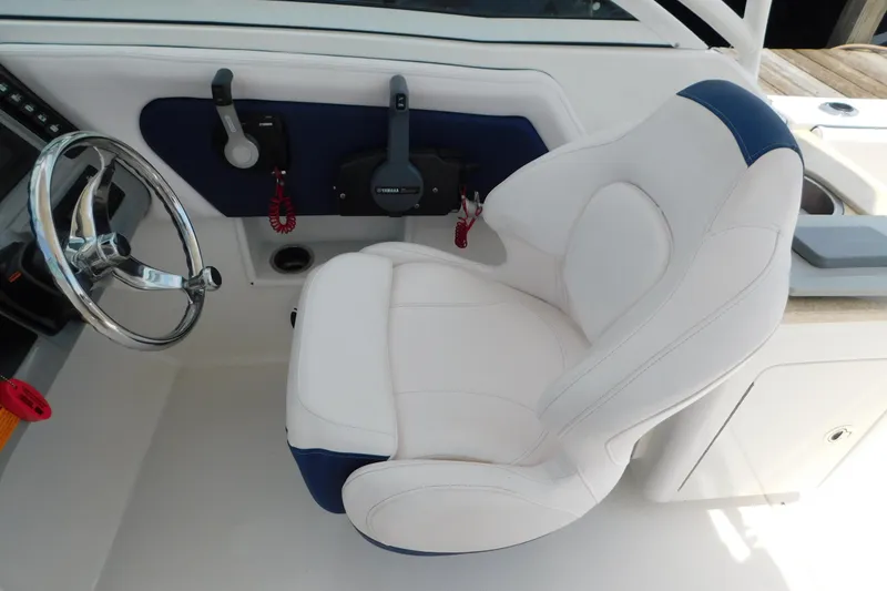 Slide: The Image of 2018 Robalo R247 Dual Console helm with white and blue captain's chair and steering wheel. - 34