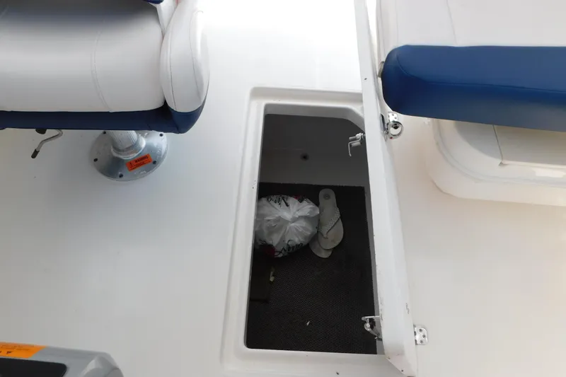 Slide: The Image of 2018 Robalo R247 Dual Console boat storage compartment with open hatch and seating. - 66