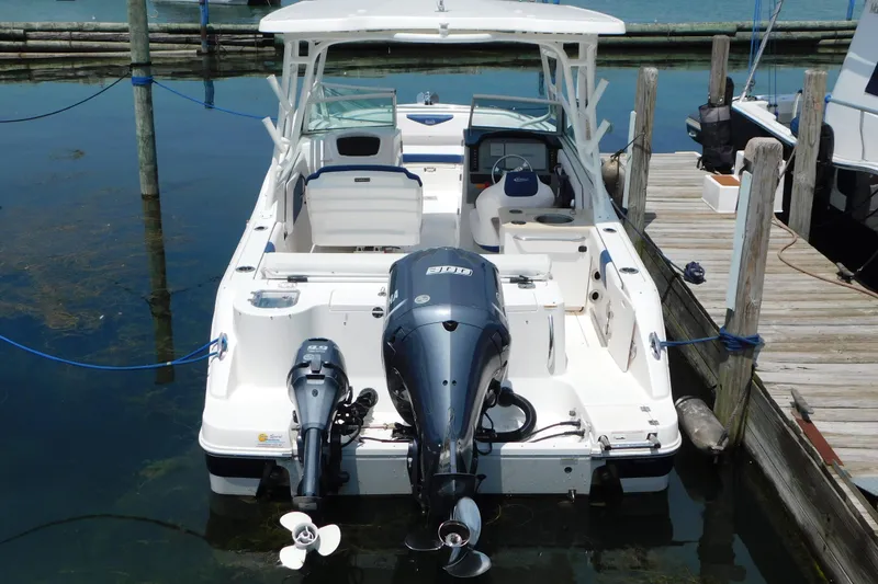 Slide: The Image of 2018 Robalo R247 Dual Console boat docked, featuring dual outboard engines. - 3
