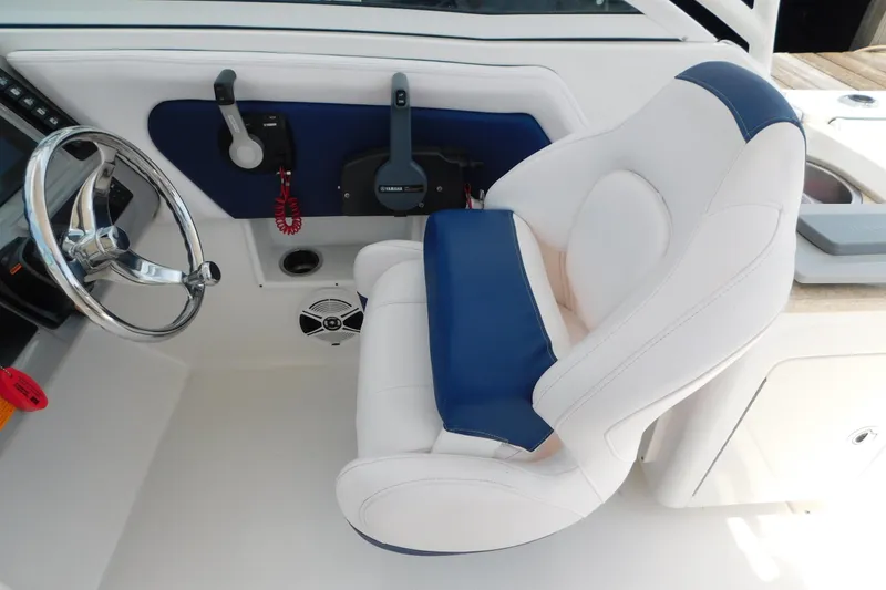 Slide: The Image of 2018 Robalo R247 Dual Console helm with white and blue captain's chair and steering wheel. - 33