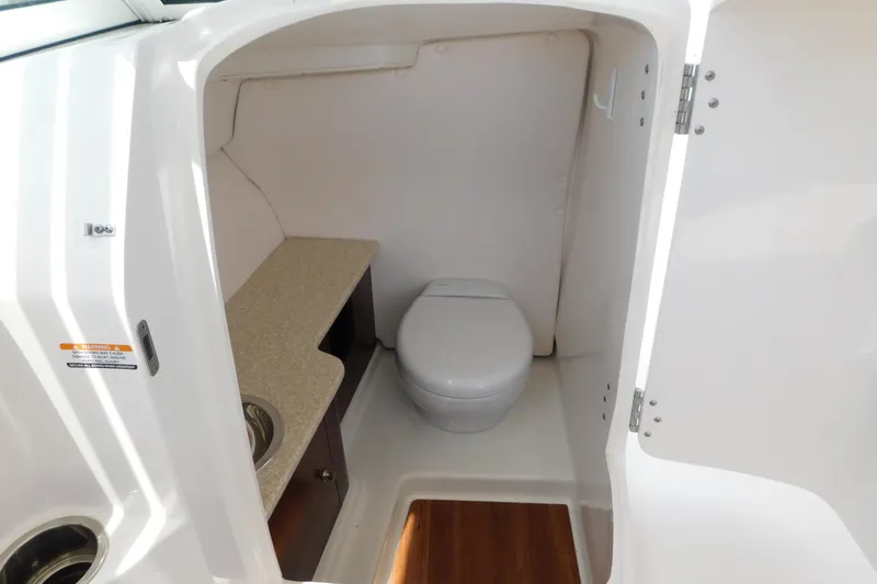 Slide: The Image of 2018 Robalo R247 Dual Console boat interior with compact marine toilet and sink. - 46