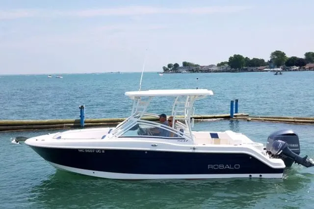 The Image of 2018 Robalo R247 Dual Console boat on calm water, featuring sleek design and powerful engine. - 0
