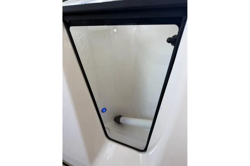 Slide: The Image of 2024 Yamaha Boats 255 FSH Sport H storage compartment with transparent door and interior view. - 14