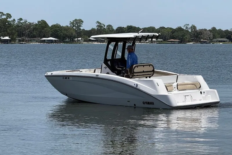 Slide: The Image of 2024 Yamaha Boats 255 FSH Sport H on calm lake waters, featuring sleek design and spacious seating. - 7