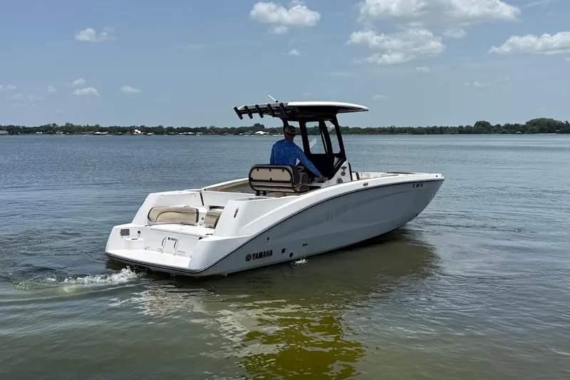 Slide: The Image of 2024 Yamaha Boats 255 FSH Sport H cruising on a calm lake under a clear sky. - 3
