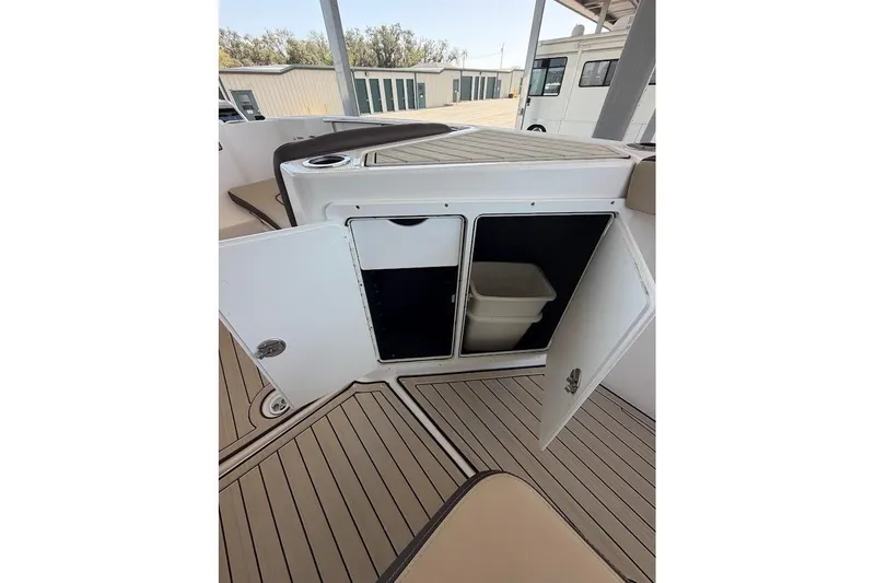 Slide: The Image of 2024 Yamaha Boats 255 FSH Sport H interior storage compartment with open doors. - 24