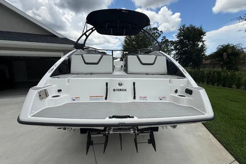 Slide: The Image of 2025 Yamaha Boats AR250, rear view, parked on driveway under cloudy sky. - 6