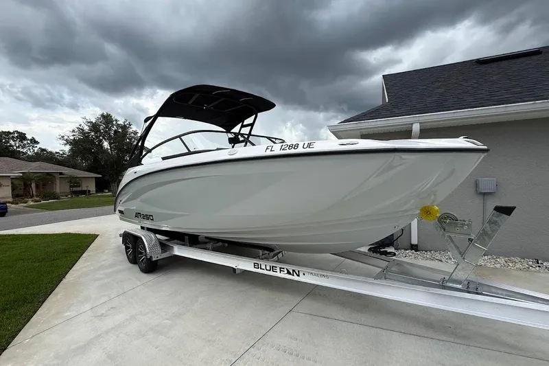 Slide: The Image of 2025 Yamaha Boats AR250 on trailer, parked in driveway under cloudy sky. - 4
