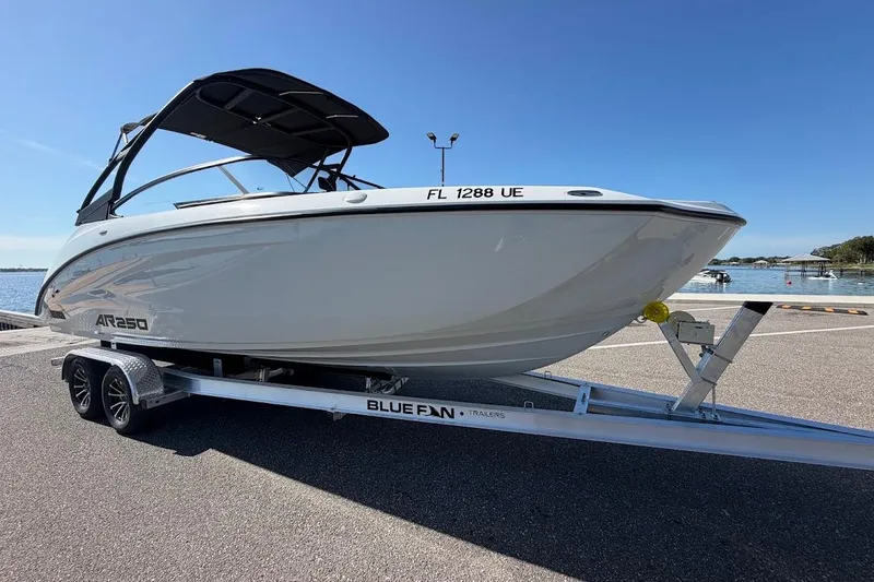 Slide: The Image of 2025 Yamaha Boats AR250 on trailer by waterfront, clear sky background. - 34