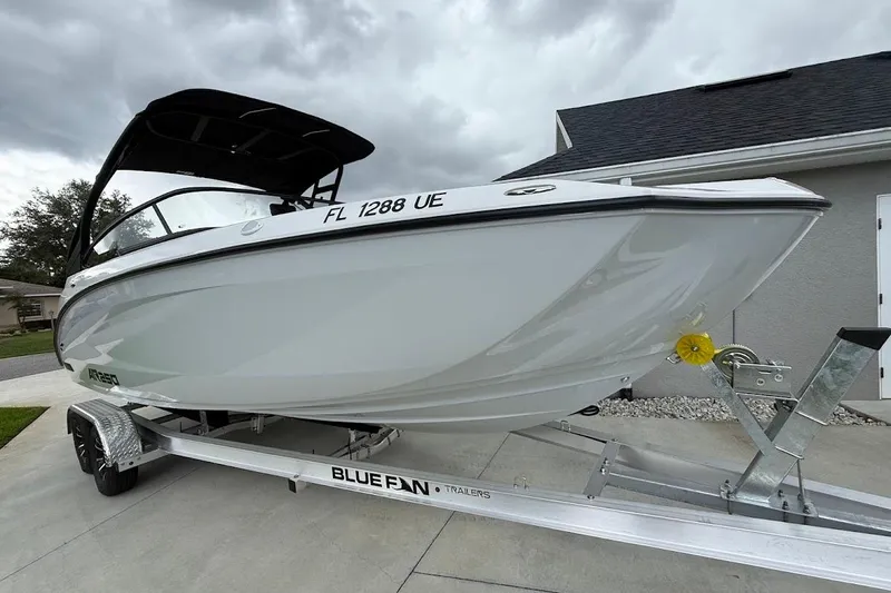 Slide: The Image of 2025 Yamaha Boats AR250 on trailer, sleek design, parked in driveway under cloudy sky. - 27