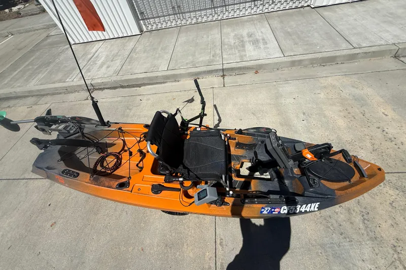 Slide: The Image of Orange OldTown Sportsman PDL 106 kayak, 2023 model, on concrete surface with fishing gear. - 2