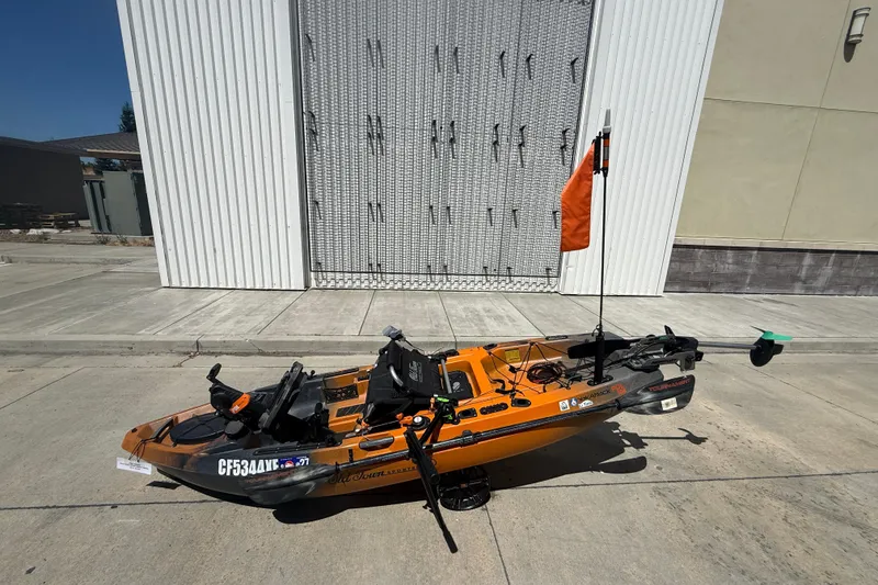 Slide: The Image of 2023 OldTown Sportsman PDL 106 kayak with orange flag, parked on concrete. - 1