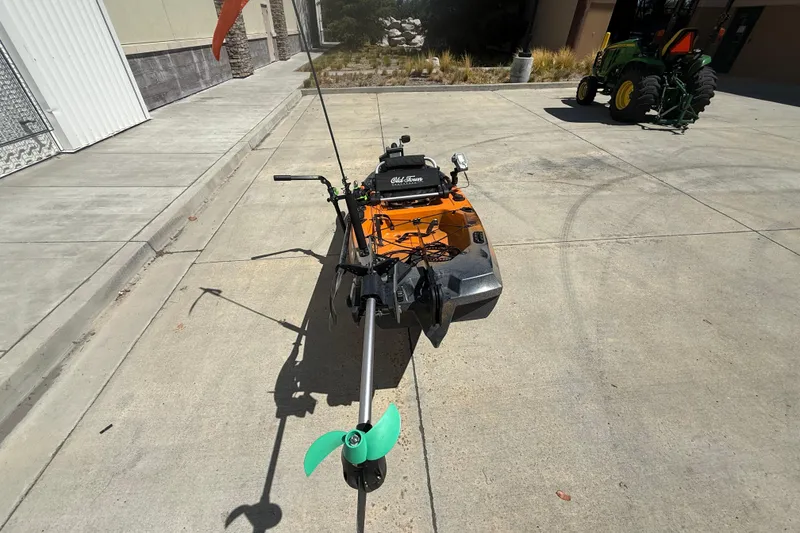 Slide: The Image of Orange OldTown Sportsman PDL 106 kayak with green propeller, parked on concrete. - 9